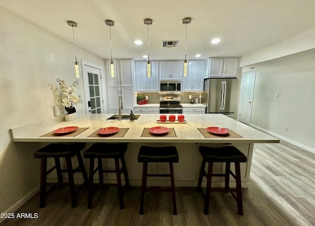 kitchen with stainless steel appliances, sink, a kitchen breakfast bar, and decorative light fixtures