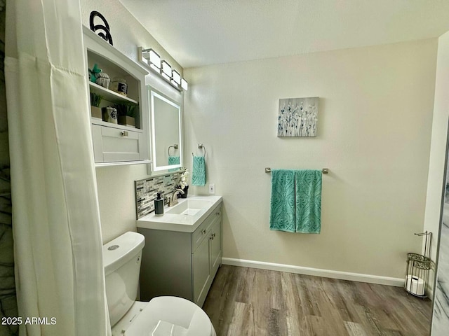 bathroom featuring hardwood / wood-style flooring, vanity, tasteful backsplash, and toilet