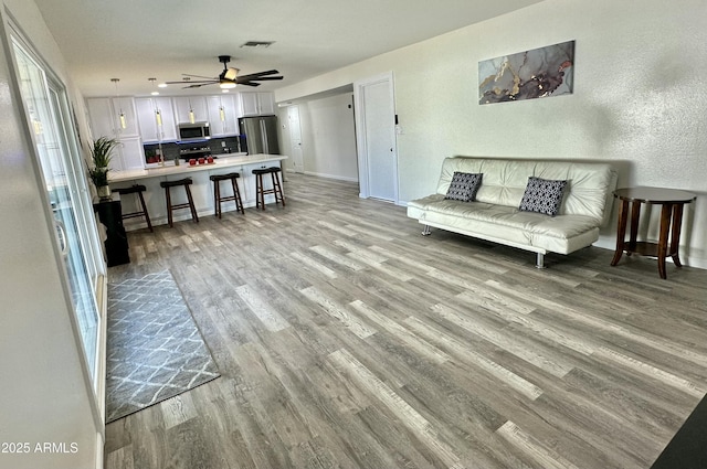 living room featuring ceiling fan and light hardwood / wood-style flooring