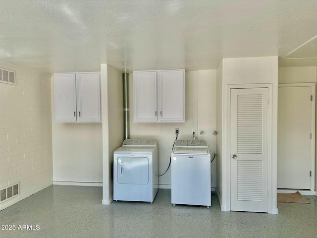 laundry area featuring a textured ceiling, cabinets, and washing machine and clothes dryer