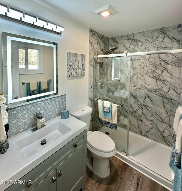 bathroom with toilet, an enclosed shower, vanity, hardwood / wood-style floors, and backsplash