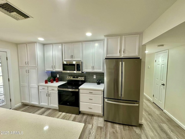 kitchen with stainless steel appliances, light hardwood / wood-style flooring, decorative backsplash, and white cabinets