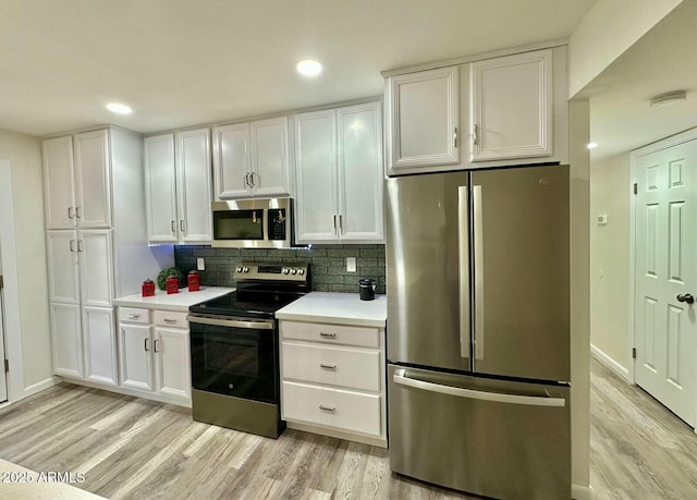 kitchen with white cabinetry, decorative backsplash, light hardwood / wood-style floors, and appliances with stainless steel finishes