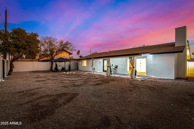 back house at dusk with a gazebo and a patio area