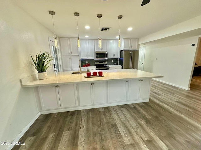 kitchen with dark hardwood / wood-style flooring, pendant lighting, stainless steel appliances, decorative backsplash, and white cabinets