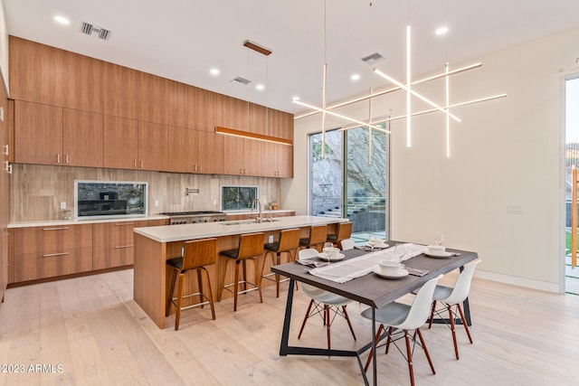 kitchen featuring light hardwood / wood-style flooring, pendant lighting, and a center island with sink