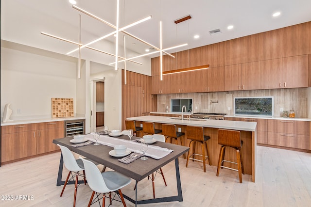 dining room with wine cooler, sink, and light wood-type flooring