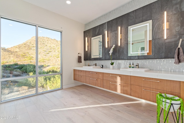 bathroom with large vanity, a mountain view, double sink, wood-type flooring, and backsplash