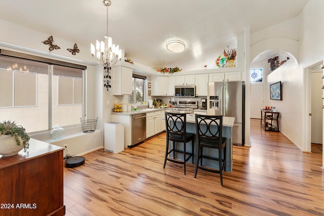 kitchen with a kitchen island, white cabinetry, light hardwood / wood-style floors, decorative light fixtures, and stainless steel appliances