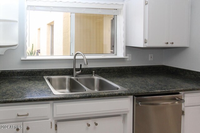 kitchen featuring stainless steel dishwasher, sink, and white cabinetry