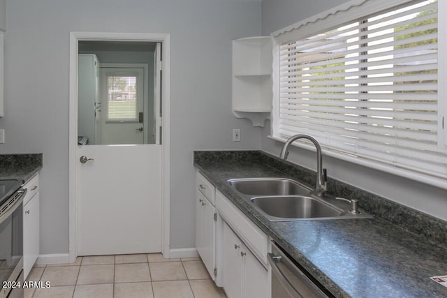 kitchen with light tile patterned flooring, appliances with stainless steel finishes, sink, and white cabinetry