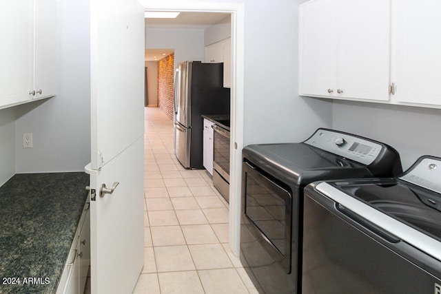 laundry room with washer and clothes dryer, light tile patterned flooring, and cabinets