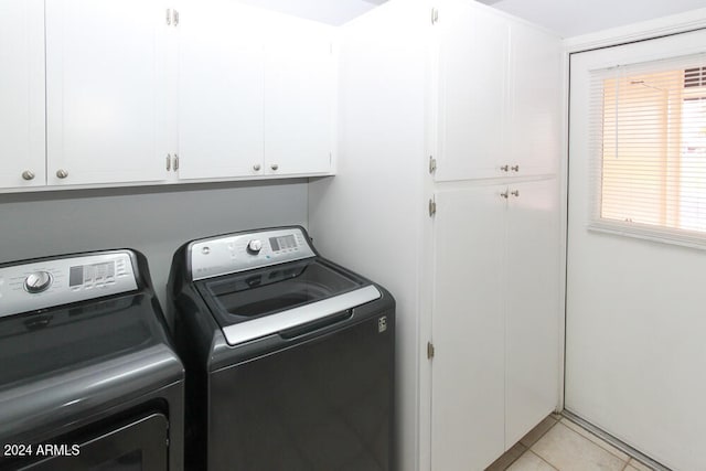 clothes washing area with washing machine and clothes dryer, cabinets, and light tile patterned floors