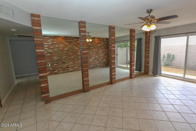 tiled empty room featuring ceiling fan and a textured ceiling