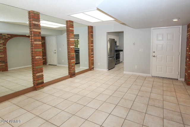 basement featuring light tile patterned flooring and stainless steel fridge