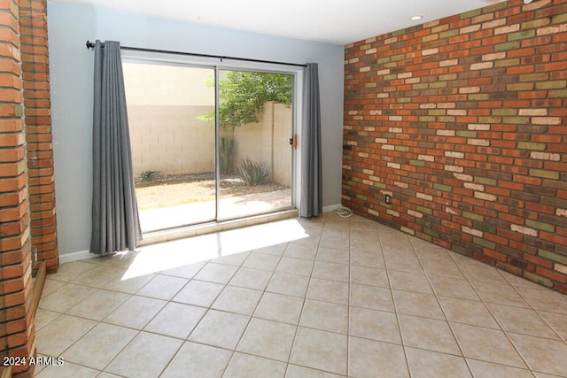 empty room featuring brick wall and light tile patterned flooring