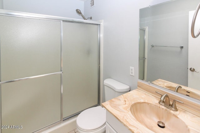 bathroom featuring vanity, a shower with shower door, and toilet