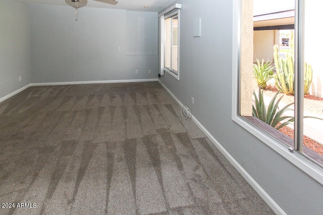 empty room featuring ceiling fan and dark colored carpet