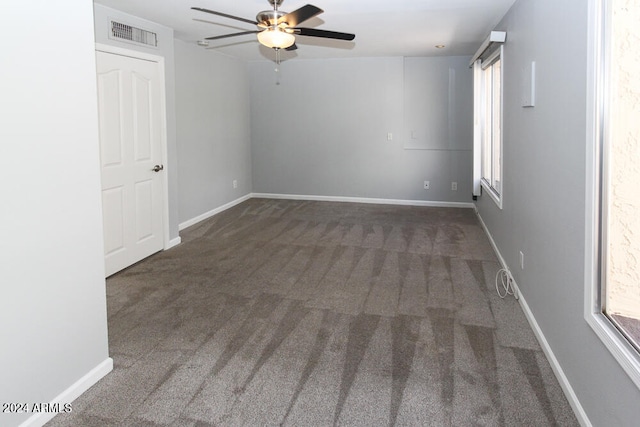 unfurnished room featuring ceiling fan, plenty of natural light, and dark colored carpet