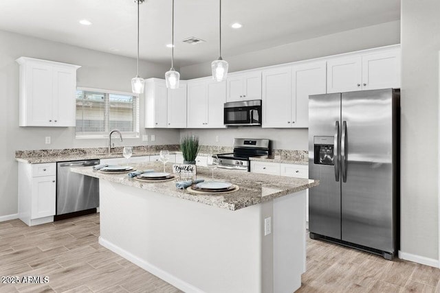 kitchen featuring stainless steel appliances, visible vents, white cabinets, a center island, and light wood finished floors