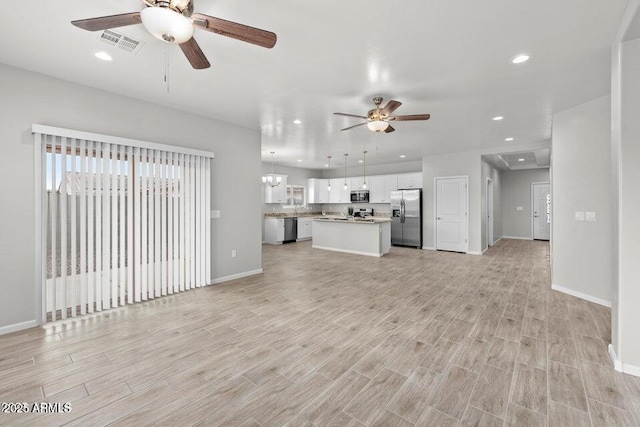 unfurnished living room with recessed lighting, visible vents, light wood-style flooring, baseboards, and ceiling fan with notable chandelier