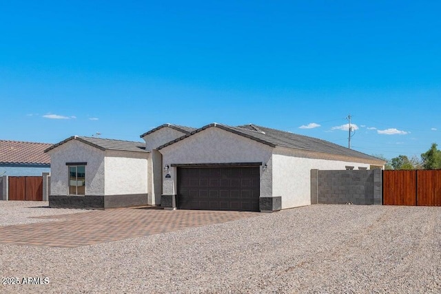 ranch-style house featuring a garage, decorative driveway, fence, and stucco siding