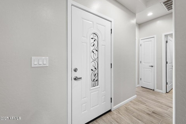 foyer with baseboards, visible vents, and light wood finished floors