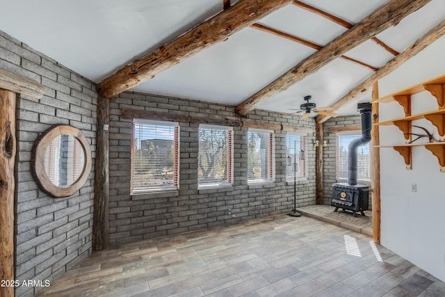 interior space featuring brick wall, ceiling fan, and a wood stove