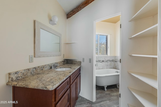 bathroom featuring beamed ceiling, a tub, and vanity