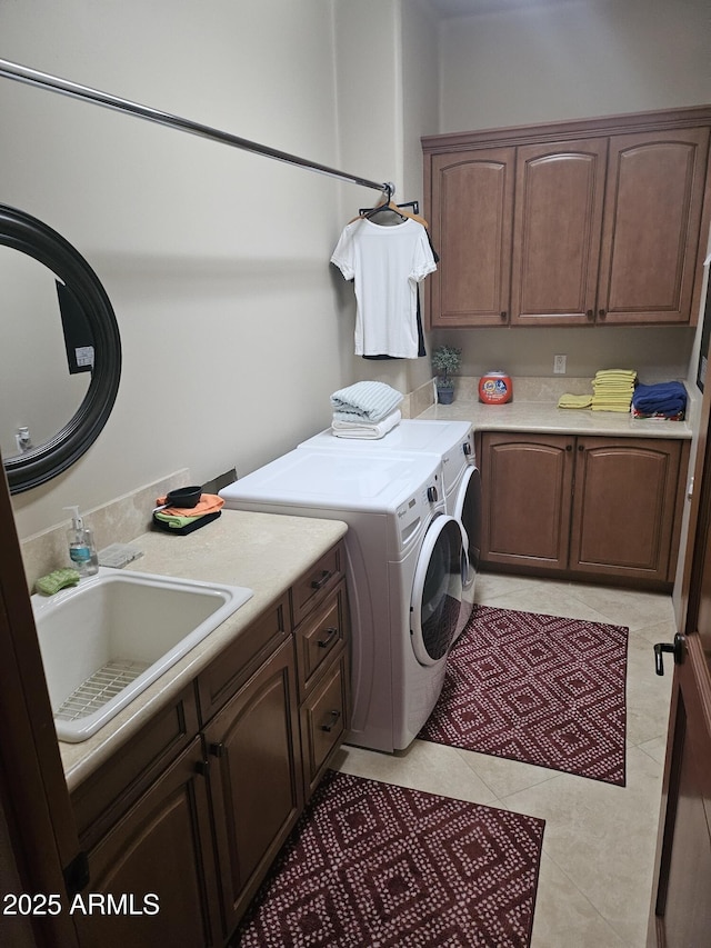 laundry area featuring cabinets, light tile patterned flooring, sink, and independent washer and dryer