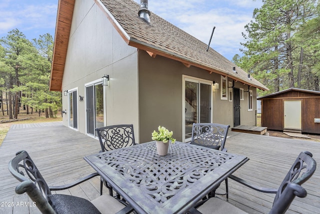 wooden deck with outdoor dining space, a shed, and an outbuilding