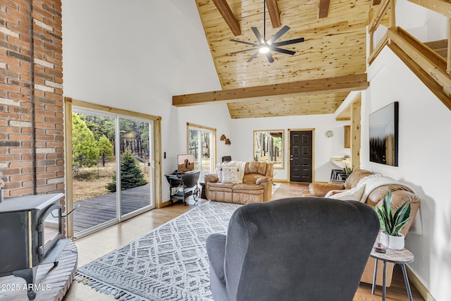 living room featuring a wood stove, beam ceiling, wood finished floors, and high vaulted ceiling