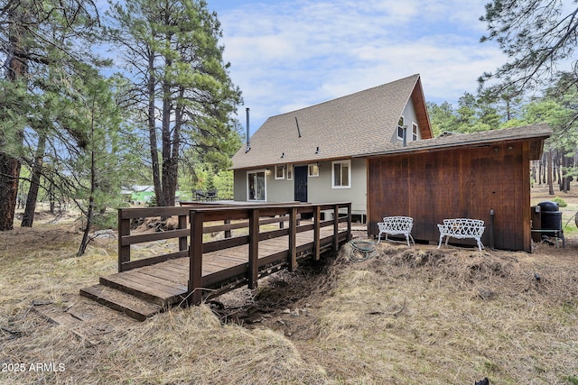 rear view of house with a wooden deck and a shingled roof