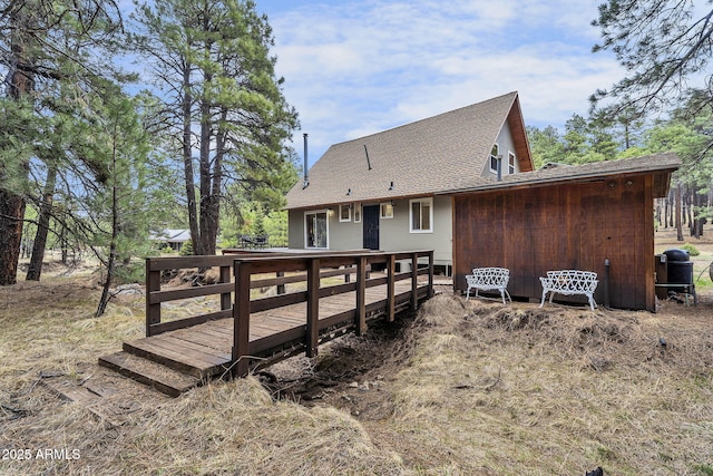 back of property with a wooden deck and a shingled roof
