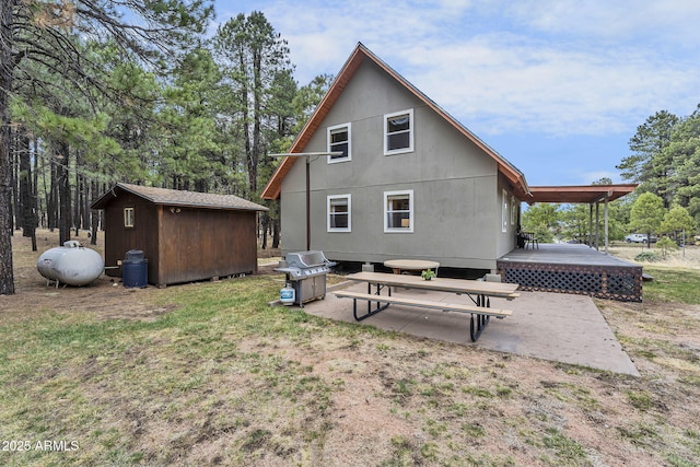 back of house featuring a patio, an outdoor structure, a deck, and a shed