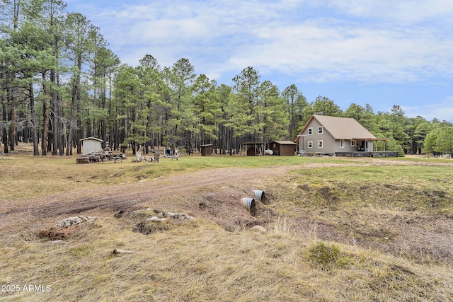 view of yard with a view of trees, an outdoor structure, and a shed