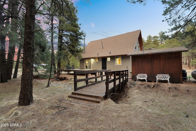 back of property with a wooden deck and a shingled roof
