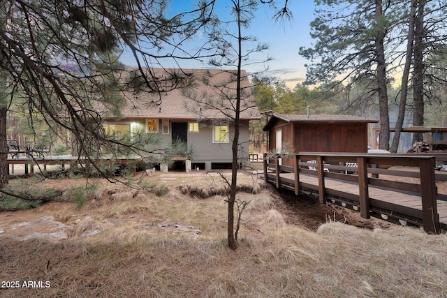 back of property with a shingled roof and a deck