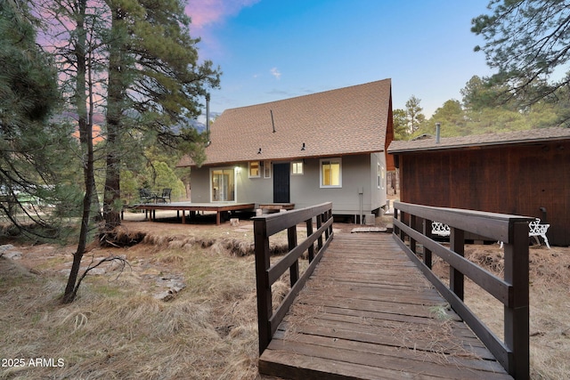 rear view of house featuring a shingled roof