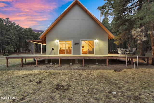 back of property at dusk with a wooden deck