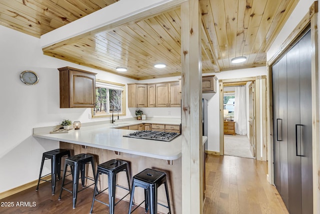 kitchen with a peninsula, wood ceiling, hardwood / wood-style floors, and a breakfast bar