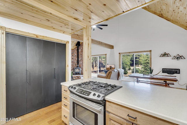 kitchen featuring light wood finished floors, open floor plan, a wood stove, wooden ceiling, and gas stove