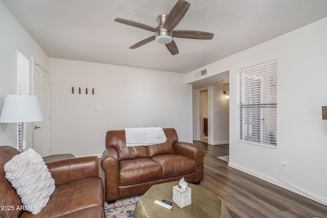 living area featuring baseboards, visible vents, wood finished floors, and a ceiling fan