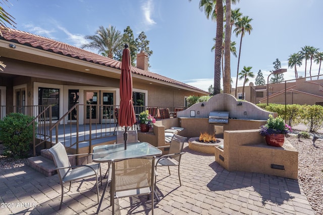 view of patio featuring outdoor dining area, an outdoor fire pit, exterior kitchen, and french doors