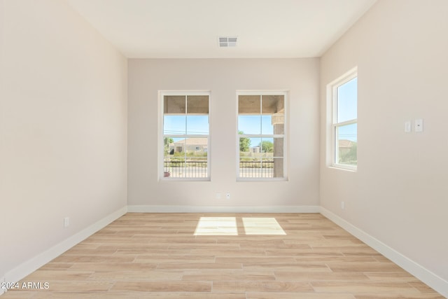 unfurnished room with visible vents, light wood-style flooring, and baseboards