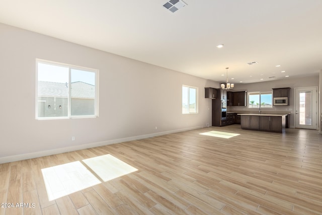 unfurnished living room with visible vents, light wood-style flooring, and baseboards