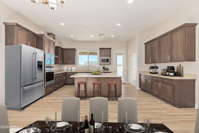 kitchen featuring stainless steel appliances, a kitchen breakfast bar, dark brown cabinets, light countertops, and a center island