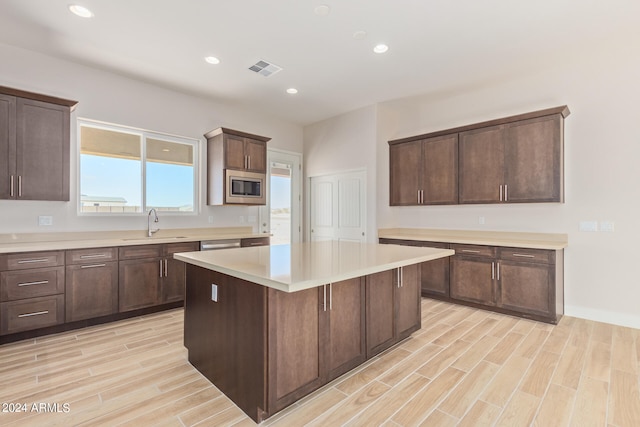 kitchen with wood finish floors, visible vents, light countertops, a center island, and stainless steel microwave