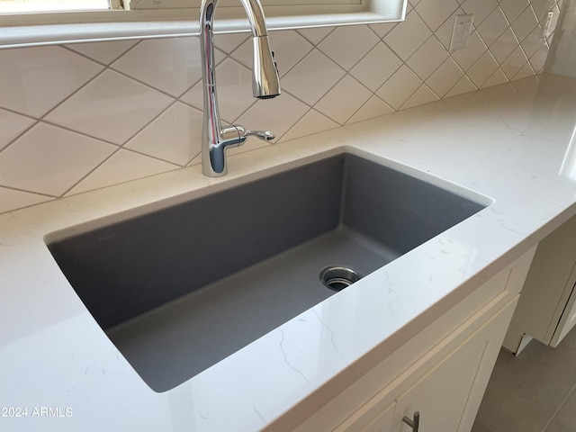 interior details with light stone countertops, decorative backsplash, and a sink