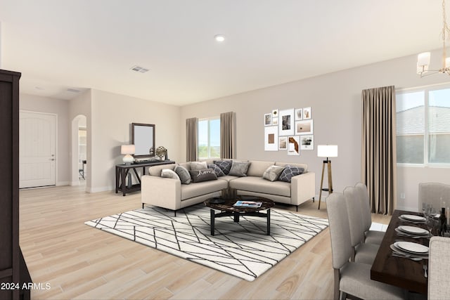 living area with arched walkways, a notable chandelier, visible vents, light wood-style flooring, and baseboards